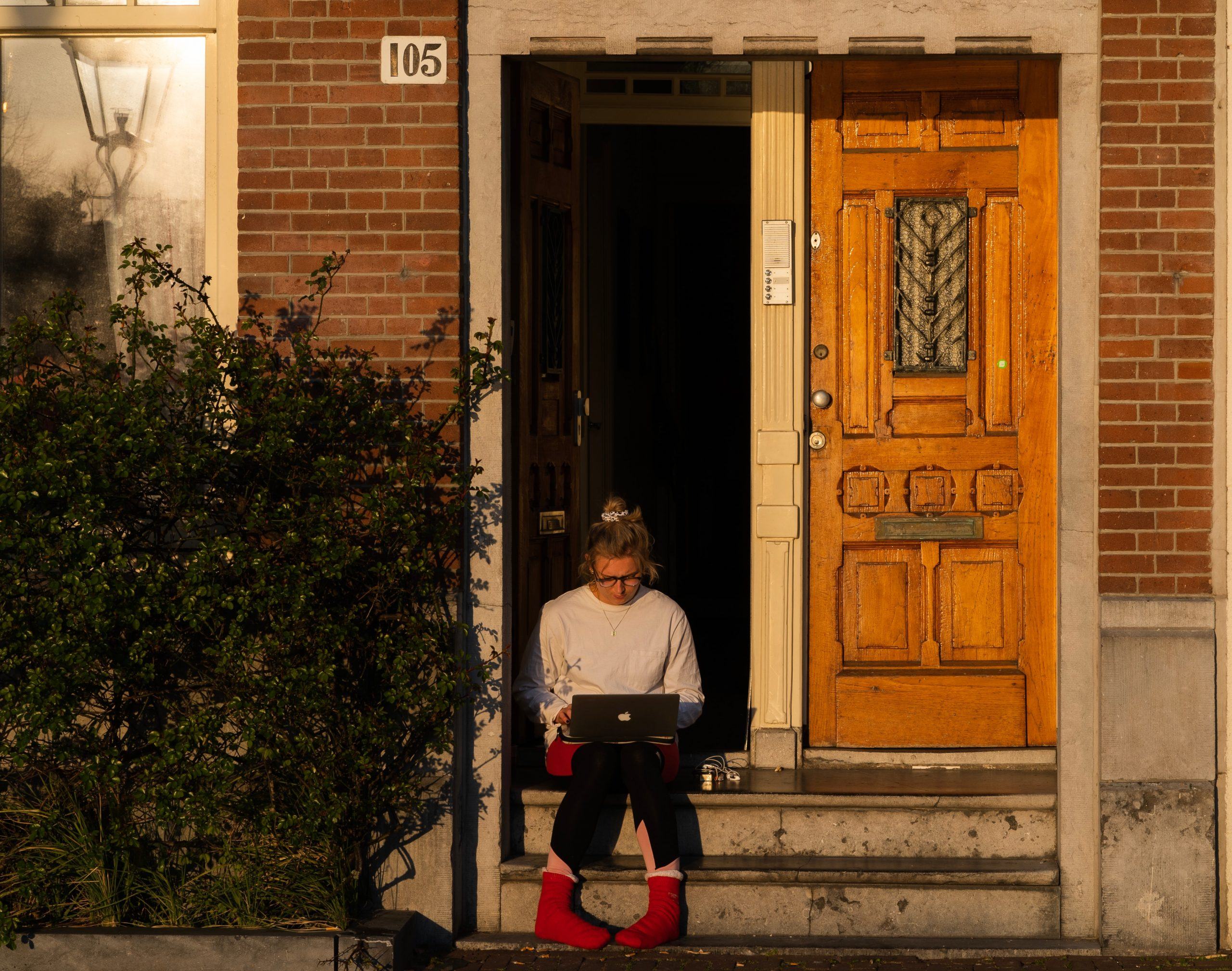 woman in white long sleeve shirt and red pants standing beside brown wooden door