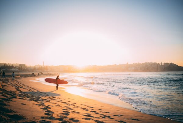 person carrying surfboard at the beach