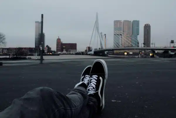 person sitting on grey concrete road in front of white suspension bridge